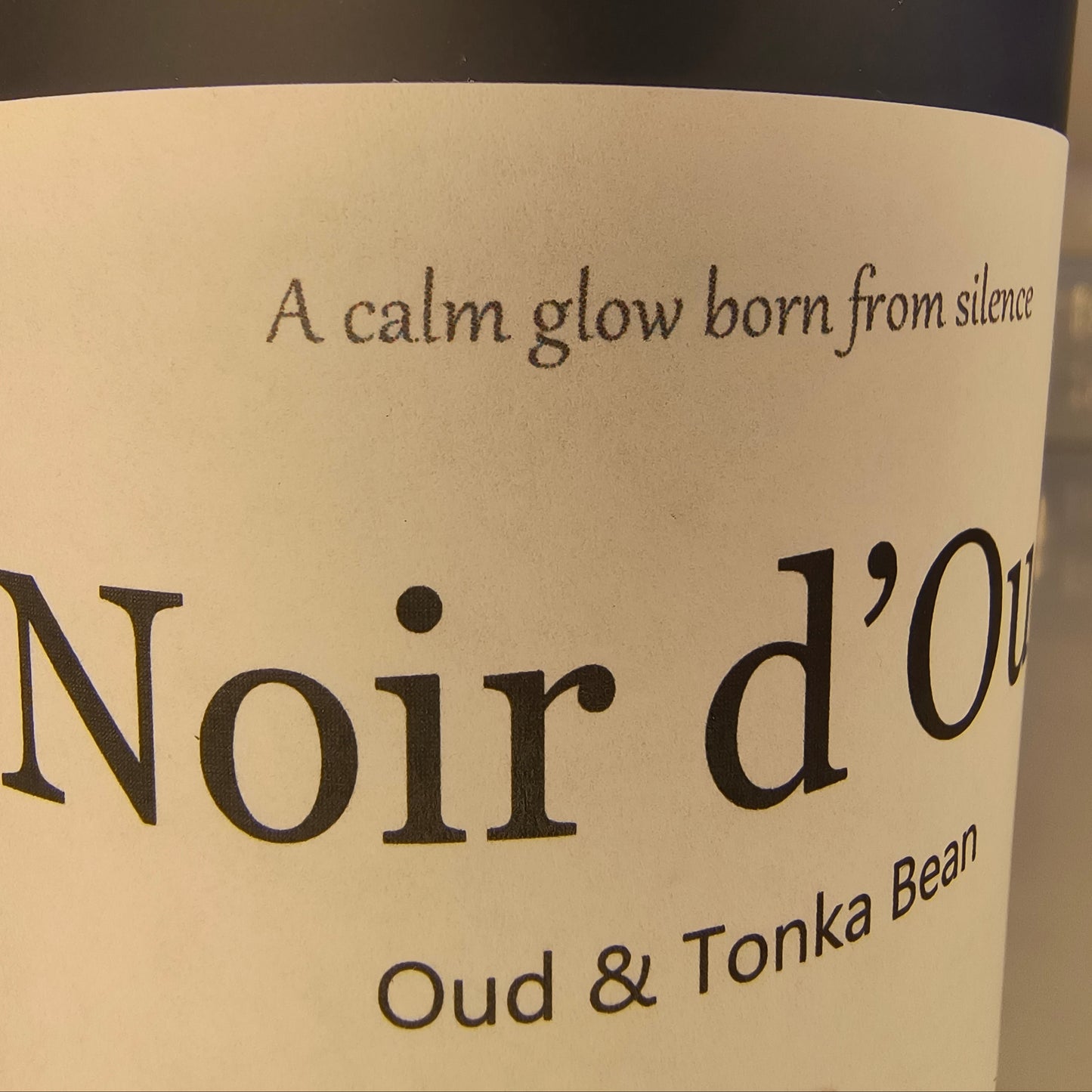 Label on a bottle of Noir d'Oud candle with text about oud and tonka bean.