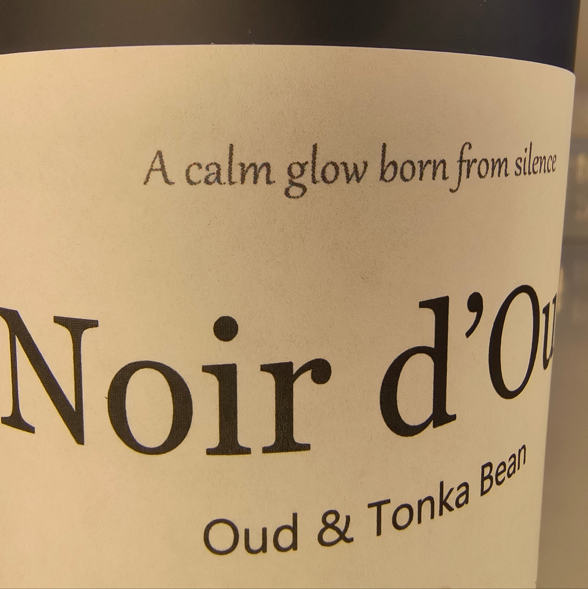 Label on a bottle of Noir d'Oud candle with text about oud and tonka bean.