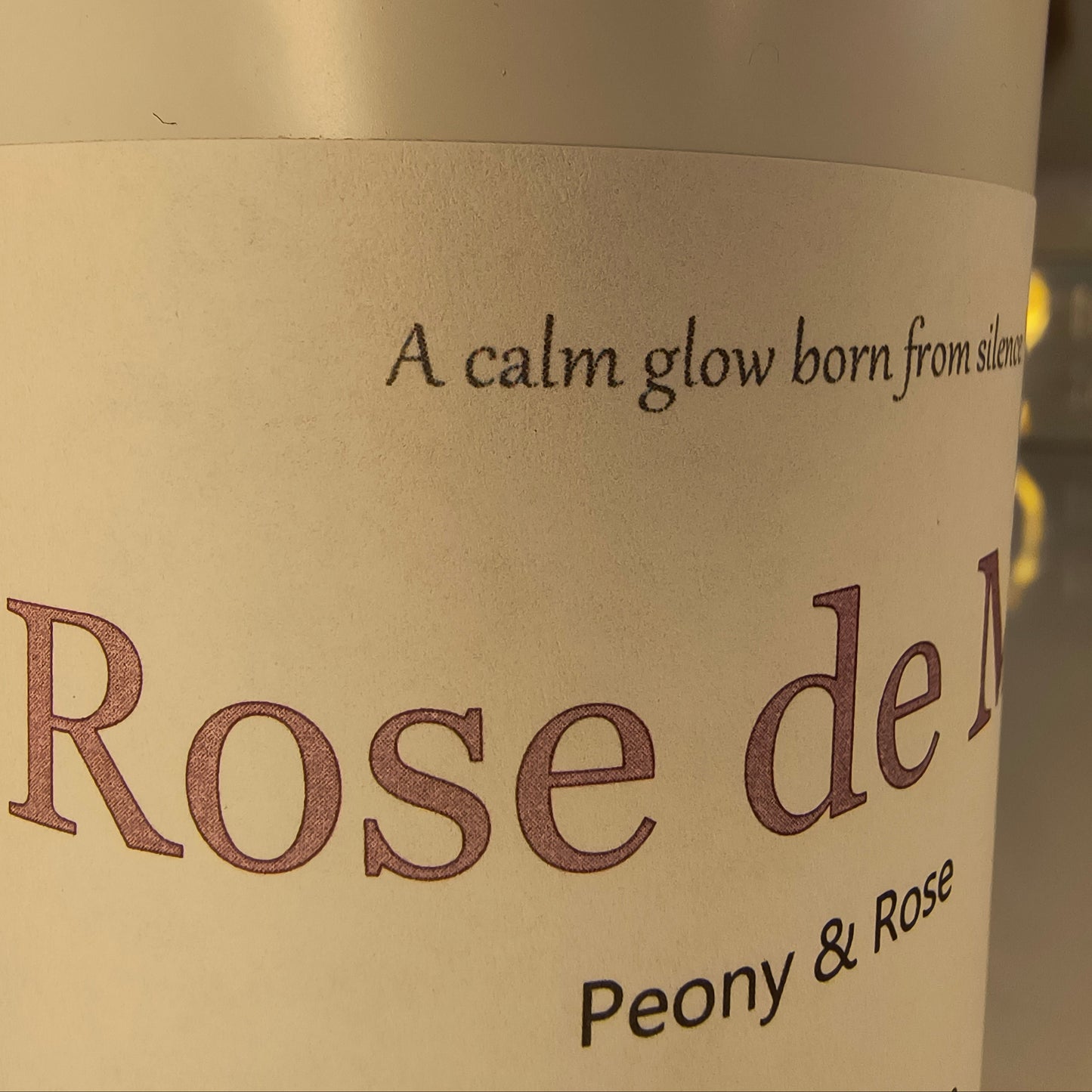 Container with 'Rose de Mer' candle on a beige background