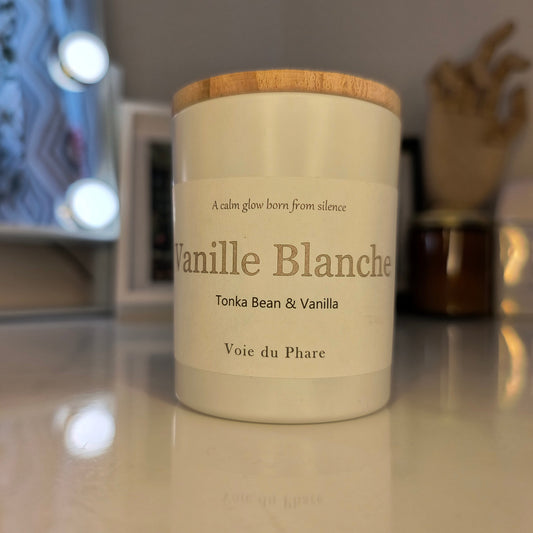 Vanilla scented candle with wooden lid on a reflective surface